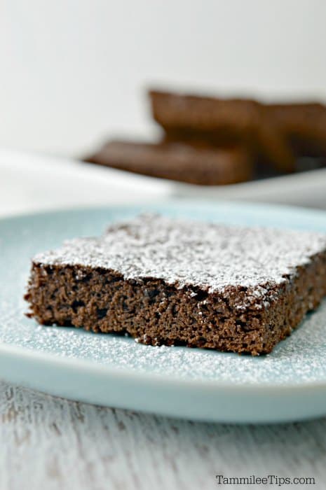 Chocolate brownie square topped with powdered sugar on a light blue plate