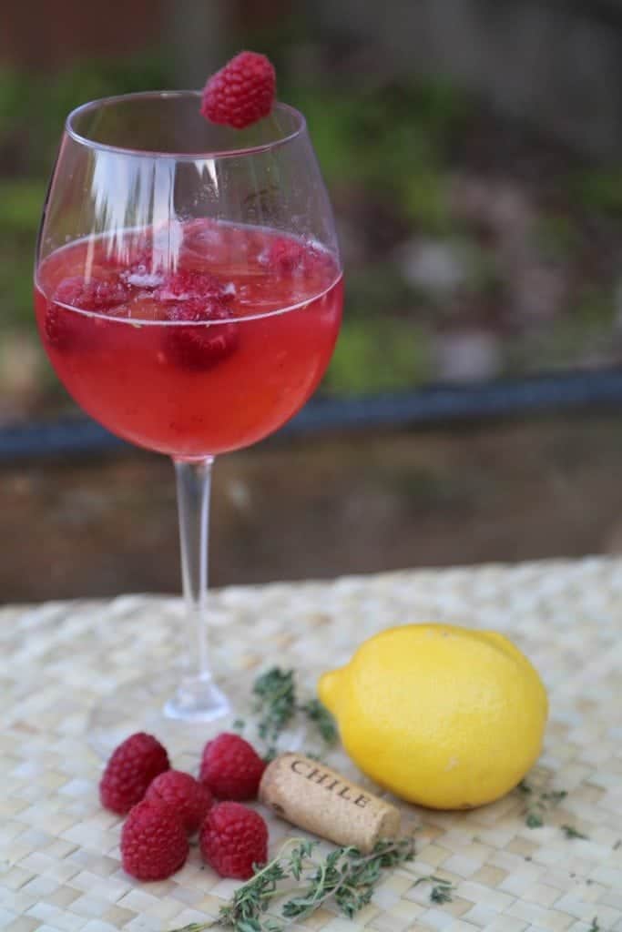 Red moscato cocktail in a wine glass with raspberries and a lemon