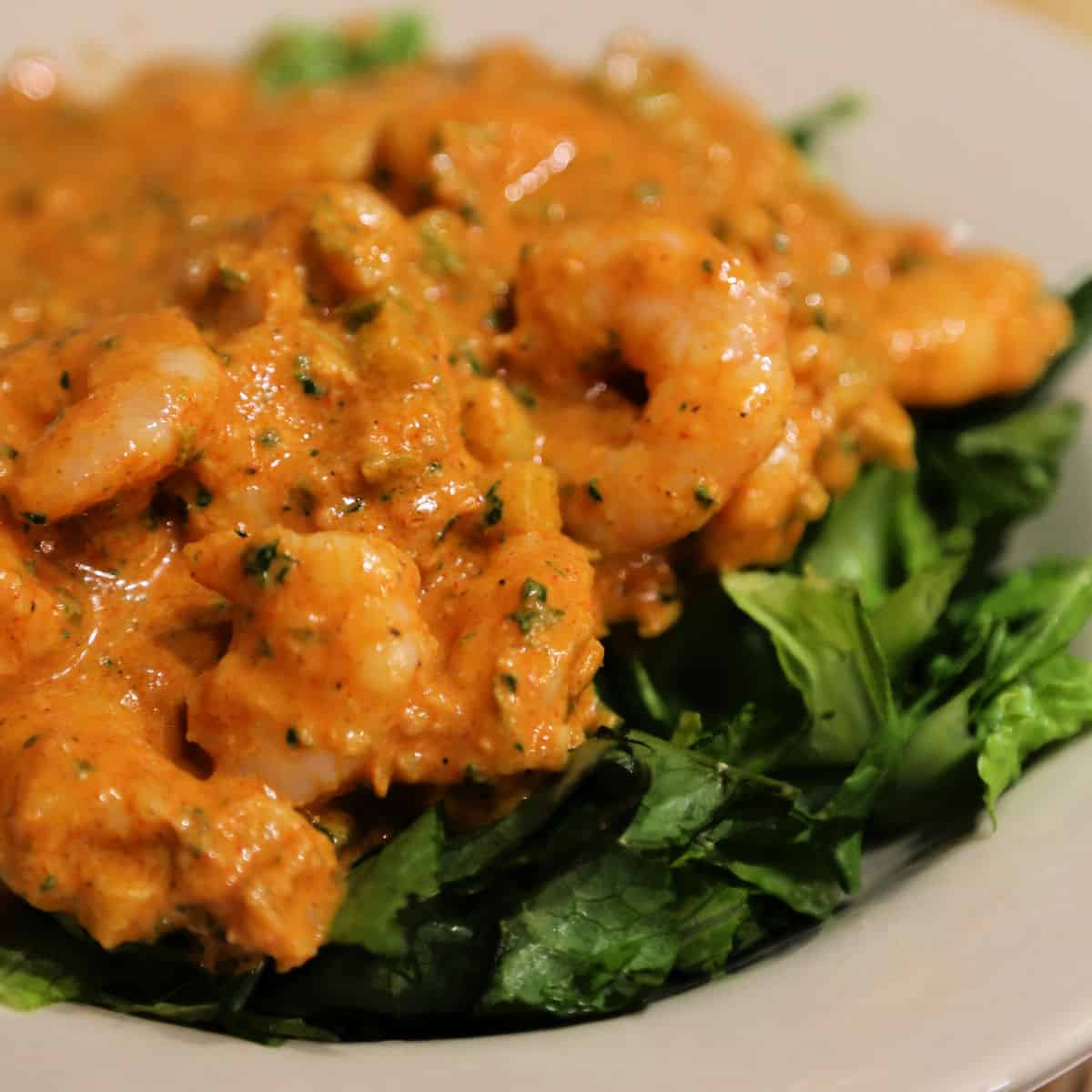 Shrimp remoulade on a bed of greens on a white plate