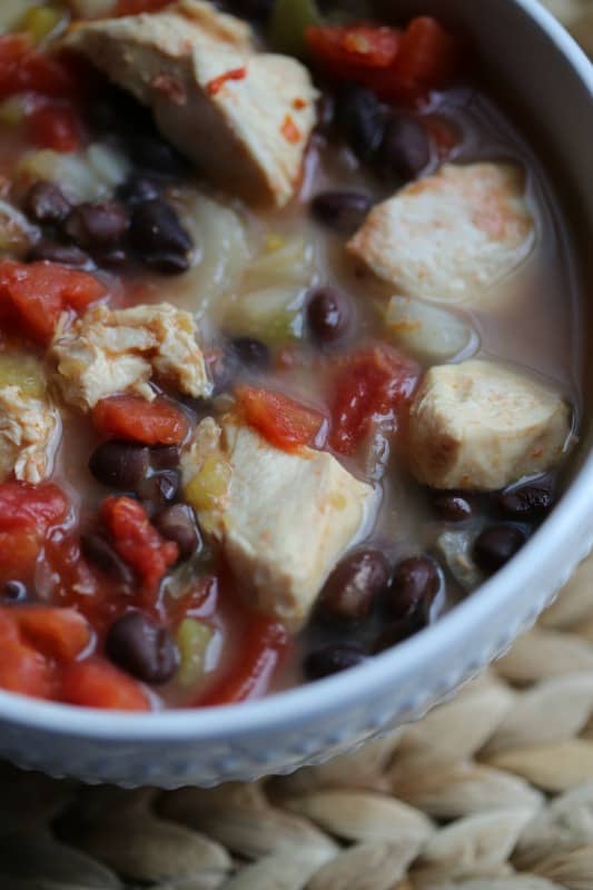 closeup of chicken chili in a white bowl on a placemat