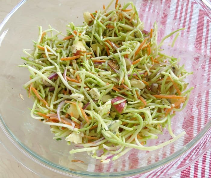 broccoli slaw in a glass bowl next to a red cloth napkin