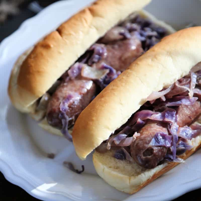 beer brats with cabbage on buns on a white plate
