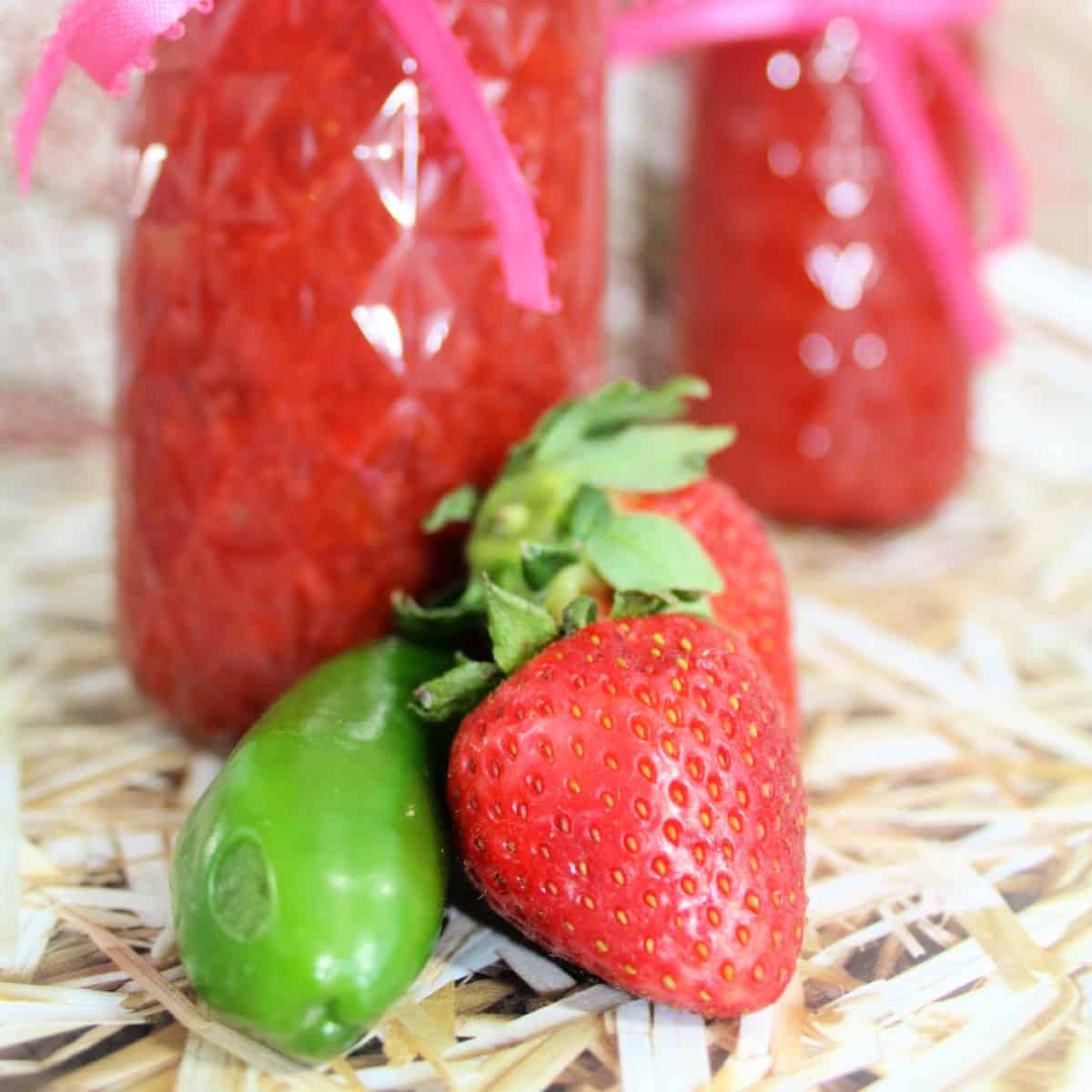 pepper and strawberry in front of strawberry chipotle jam jars