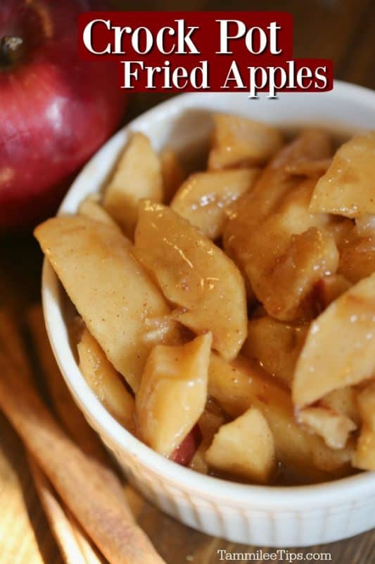 Crockpot Fried apples over a white bowl with apples, cinnamon sticks, and a red apple