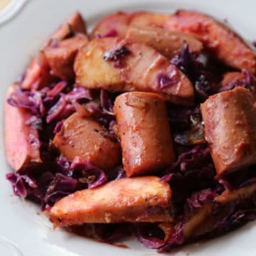 kielbasa, red cabbage, and apples on a white plate