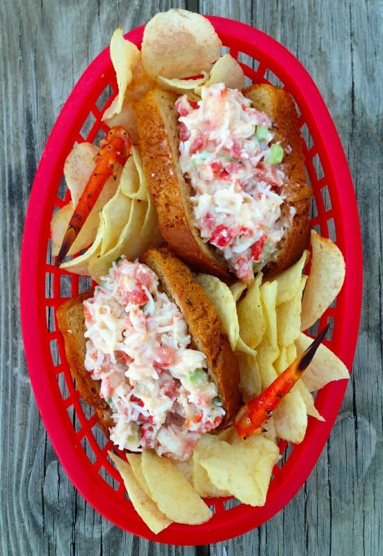 Two crab rolls with potato chips on a picnic table