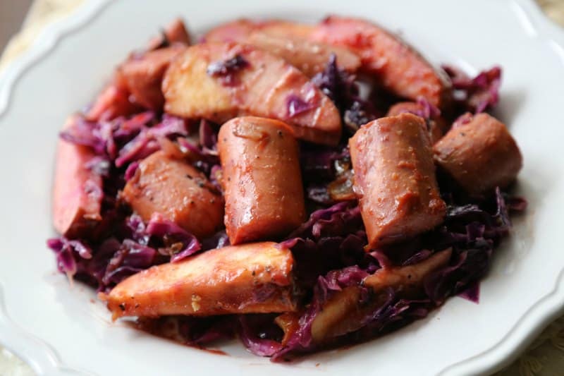  white plate with cooked kielbasa, apples, and cabbage