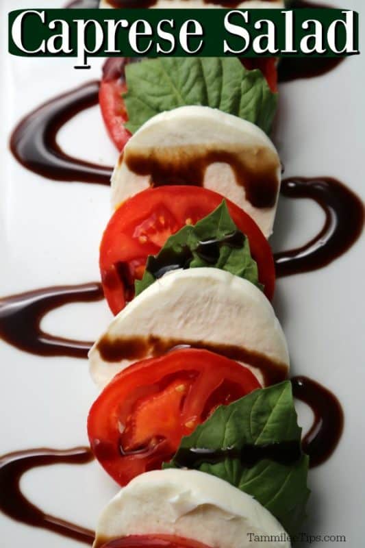 Caprese Salad over a white platter with tomato slices, basil, and mozzarella cheese covered in balsamic glaze