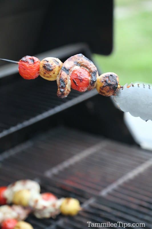 Tongs holding Ranch Steak Kabobs over the barbecue