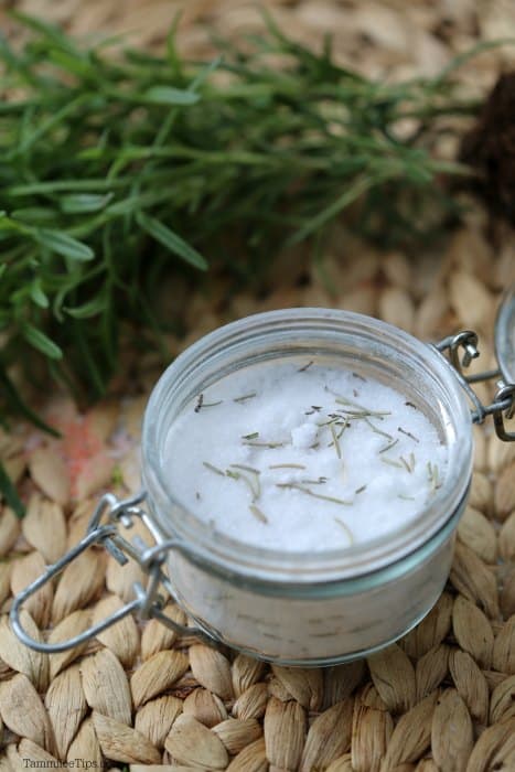 rosemary bath salts in a glass container next to a handful of rosemary