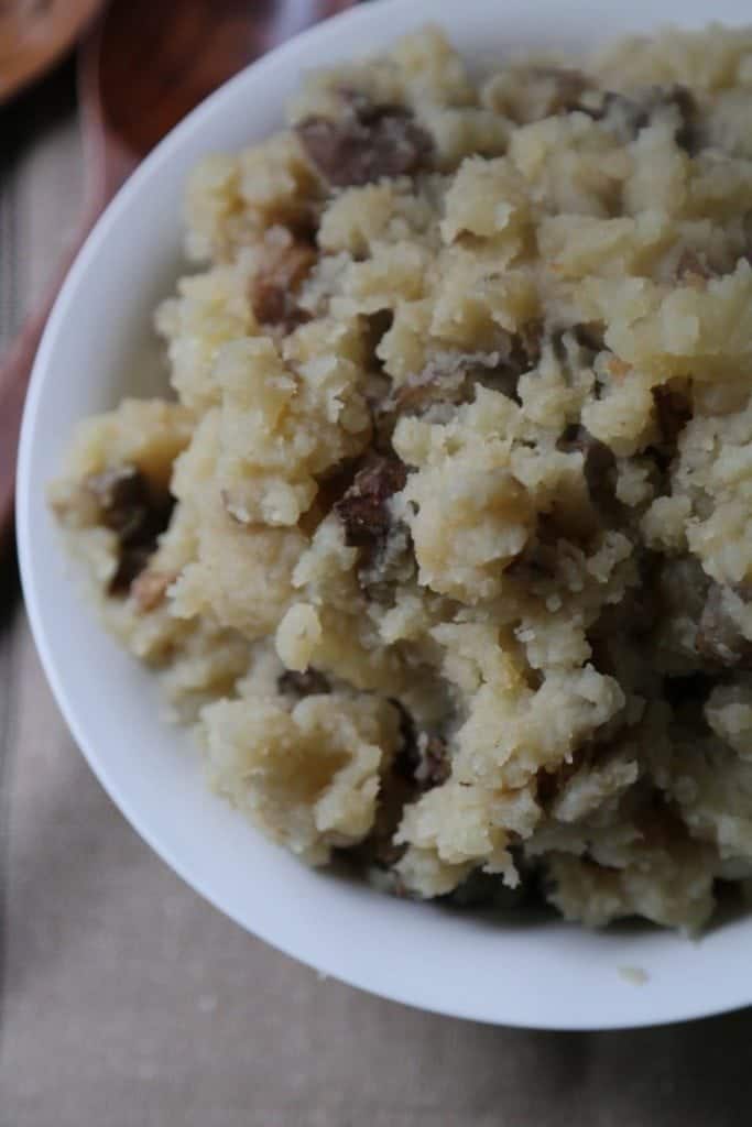 Crock Pot Garlic Mashed Potatoes Recipe in a white bowl on a brown placemat