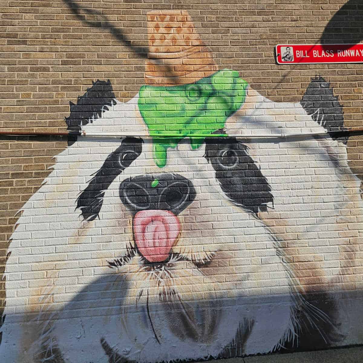 Panda Mural with an ice cream on the pandas head and its tongue sticking out on a brick wall