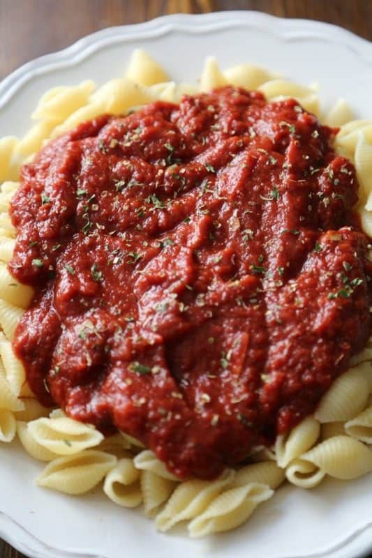 a white plate with marinara sauce on pasta shells 