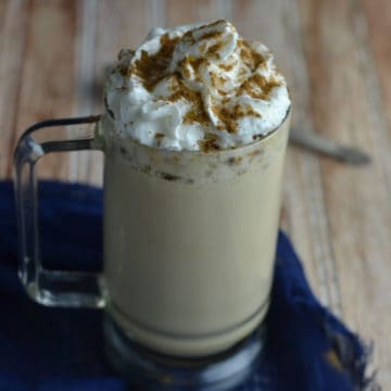 Eggnog latte in a glass mug topped with whipped cream and cinnamon