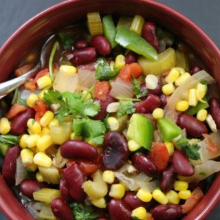 Crockpot Vegetarian Chili text over a red bowl with beans avocado and corn