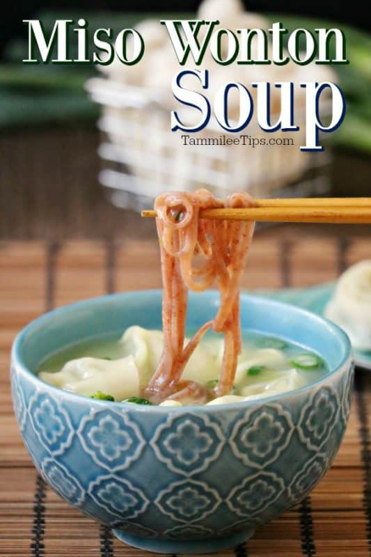 Miso wonton soup over a blue bowl with chopsticks holding noodles