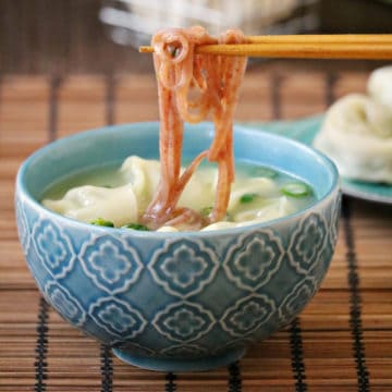 chopsticks holding noodles over Miso Wonton & Noodle Soup in a blue bowl