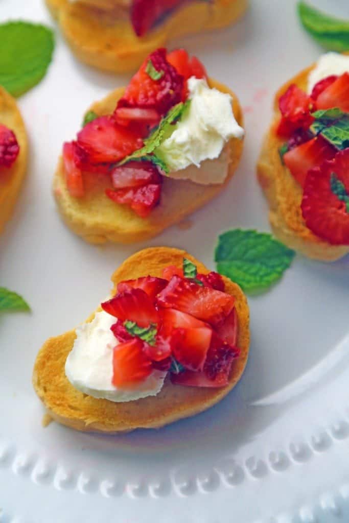 Strawberry Bruschetta on a slice of toast with ricotta cheese on a white plate