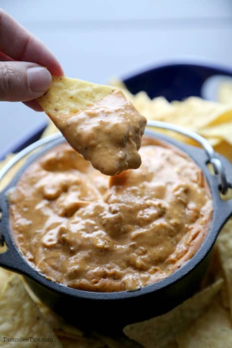 hand holding a chip dipping into chili's queso