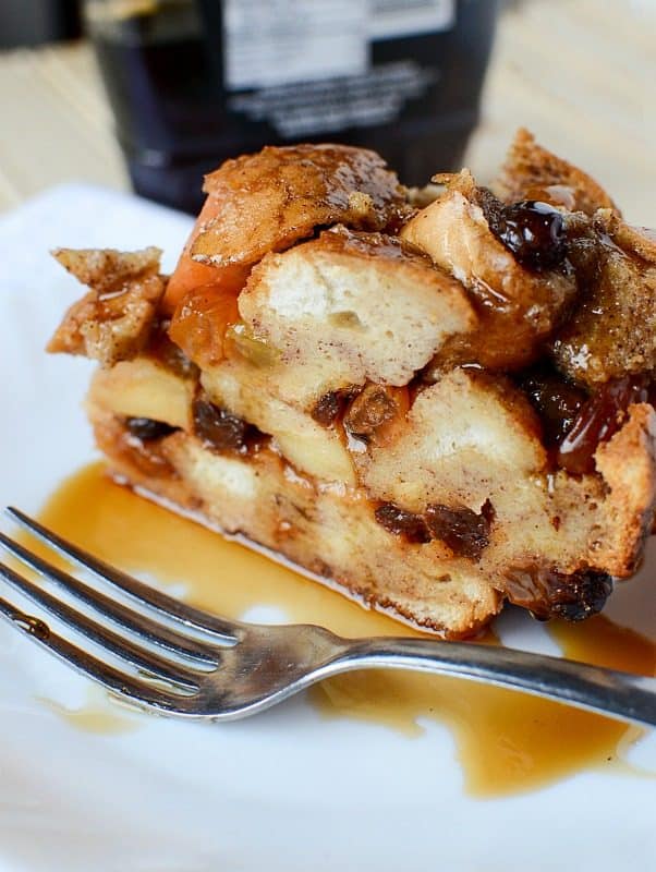 Crock Pot Apple Raisin French Toast on a white plate with syrup and a silver spoon