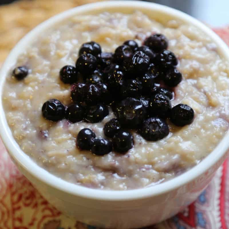 crockpot blueberry oatmeal in a white bowl with blueberries on top