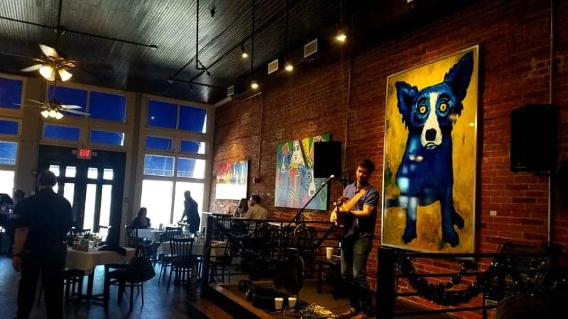 Blue dog painting on the wall with a singer below it