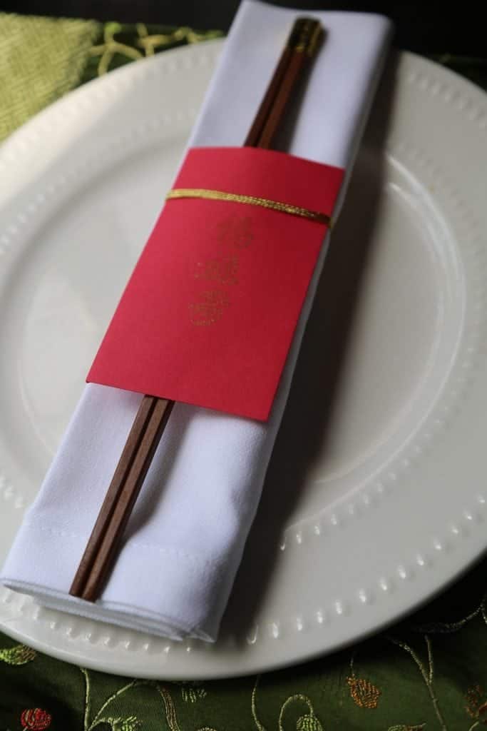 Chinese Envelopes wrapped around a pair of chopsticks and white napkin on a white plate