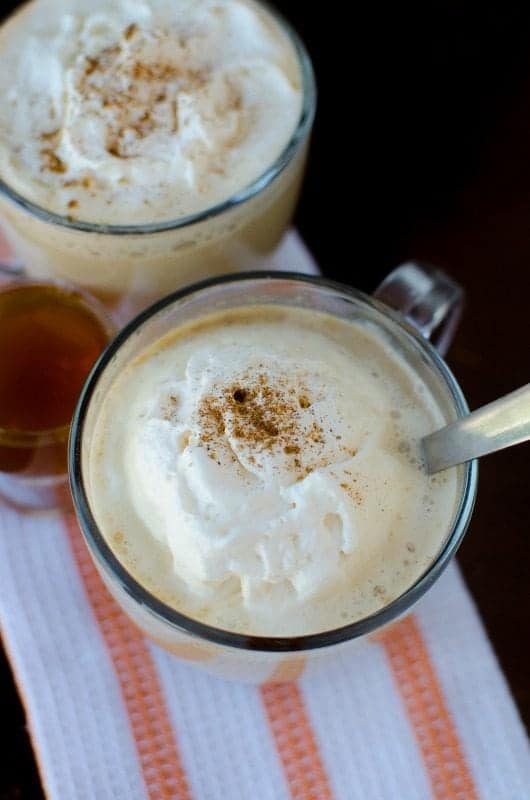 2 Crockpot pumpkin spice lattes in glass mugs on a white and orange towel. 