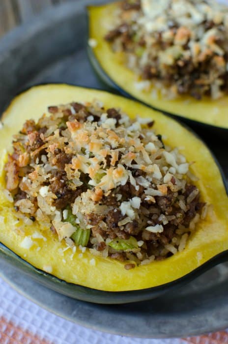 stuffed acorn squash with sausage and rice on a plate on a cloth napkin