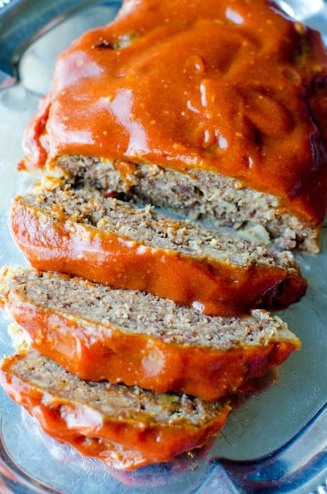 crock pot meatloaf sliced on a silver platter with meatloaf sauce over it. 