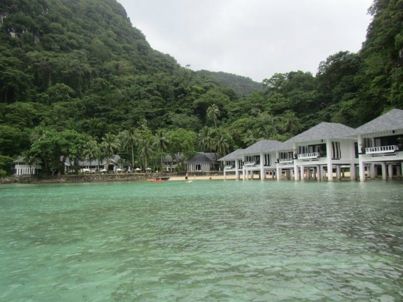 overwater bungalows on a lagoon with palm trees in the background