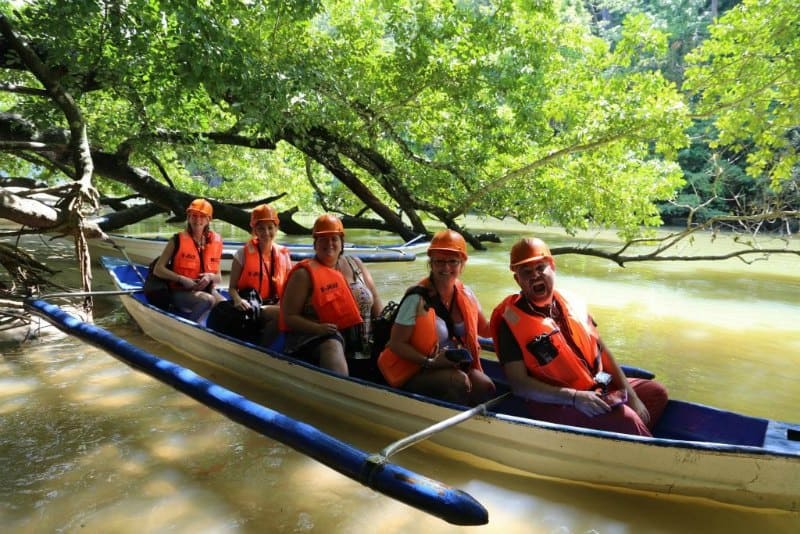 5 people in orange life jackets in a small outrigger canoe boat