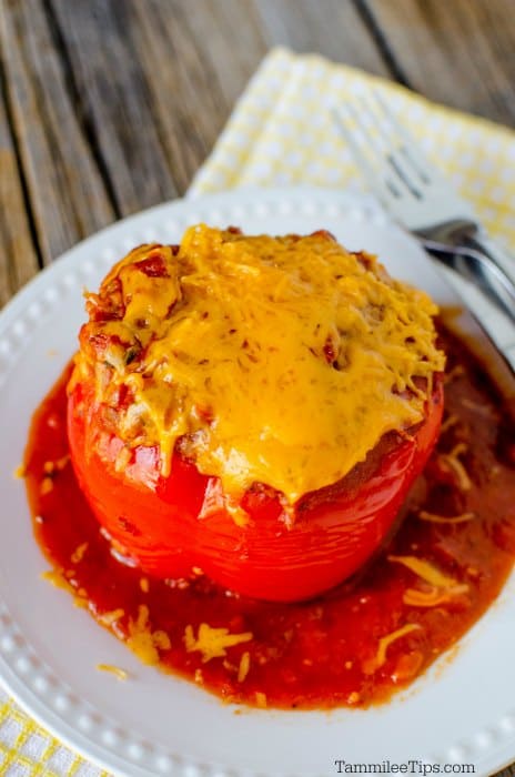 crockpot stuffed pepper with cheddar cheese sitting on a white bowl with a yellow napkin on a brown wood background