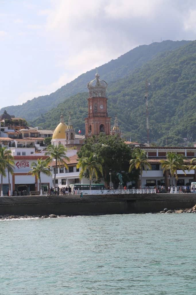 historic clock seen from the water with Senor frogs and tropical forests. 