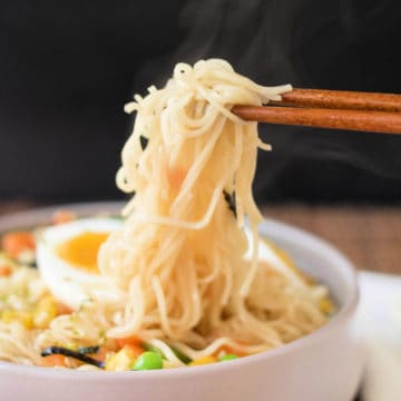 chopsticks holding noodles above an easy ramen bowl