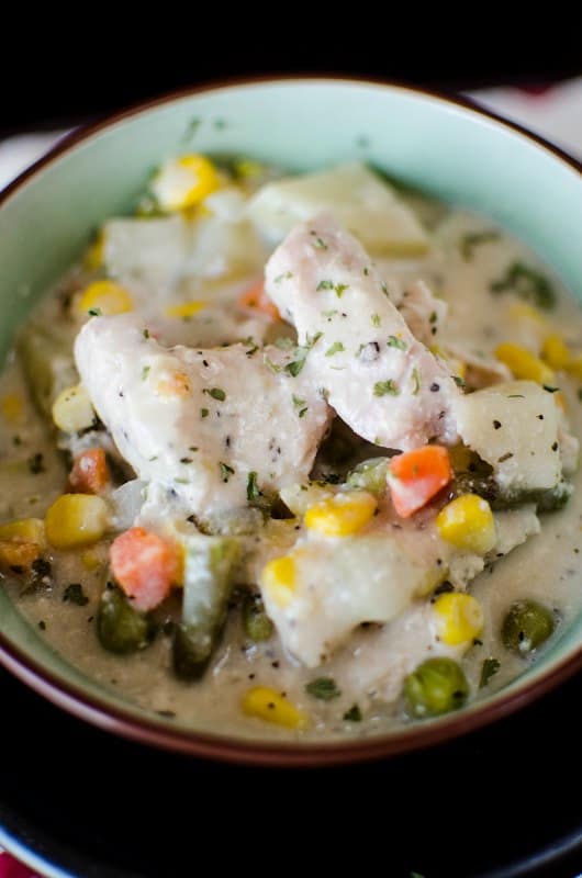 Green bowl filled with chicken, vegetables, and stew