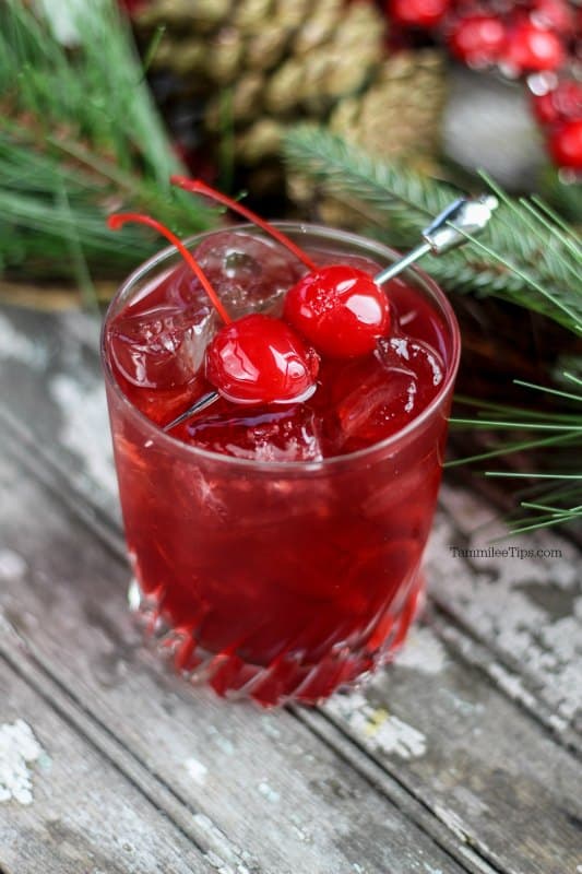 red cocktail with two maraschino cherries for a garnish
