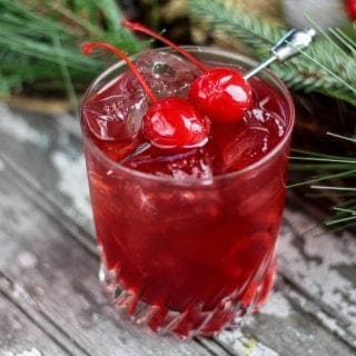 Mulled cherry cider cocktail in a glass with greenery around it