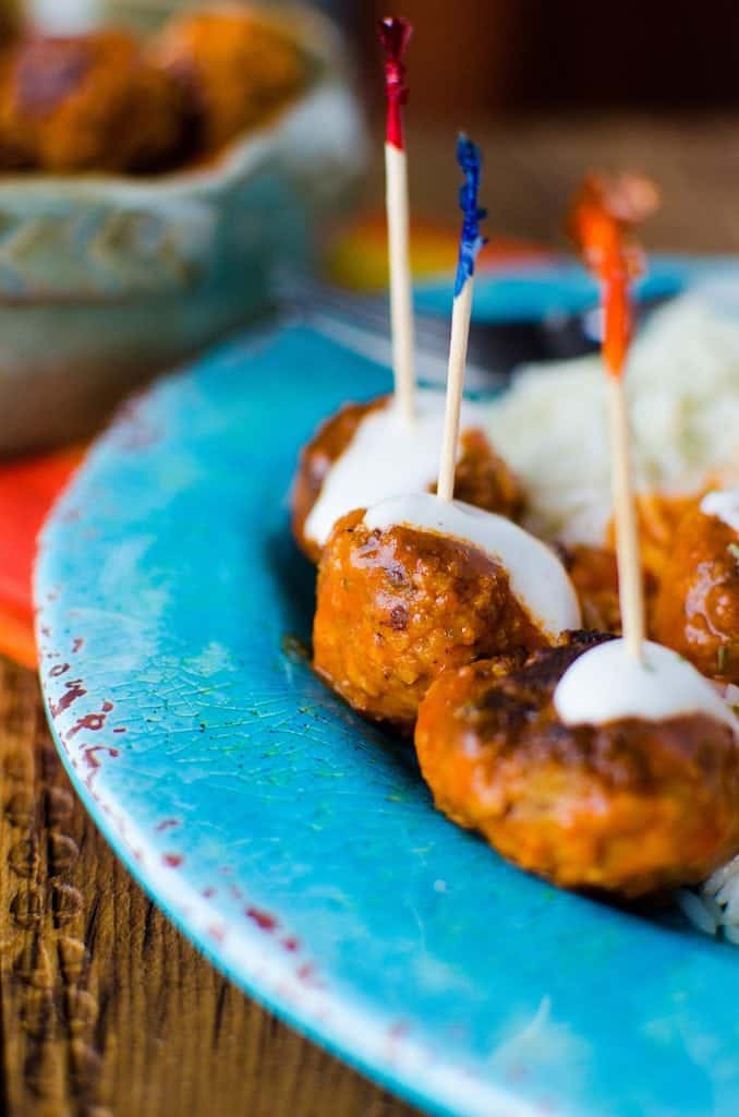 Crockpot buffalo chicken meatballs on a blue plate with toothpicks in them