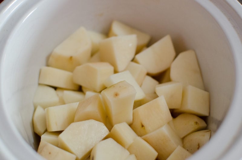 Cubed potatoes in a white slow cooker bowl