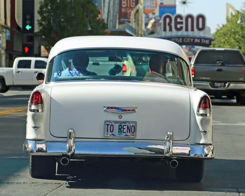 Historic white classic car in front of the Reno sign. 