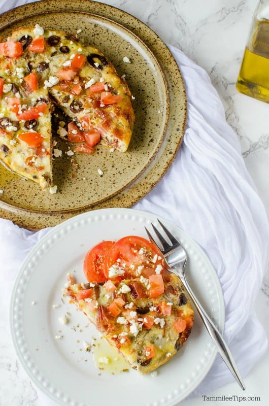 plate with a slice of Greek frittata and tomatoes, next to serving dish. 
