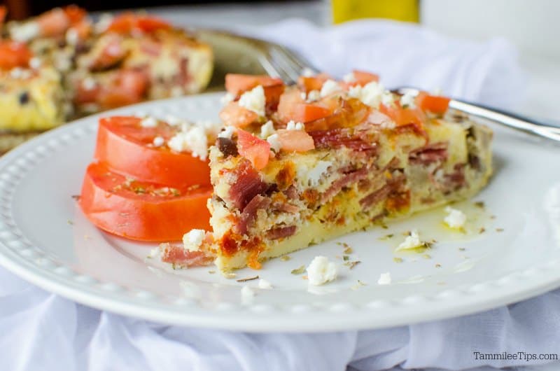 plate with a slice of Greek frittata and tomatoes, next to serving dish. 