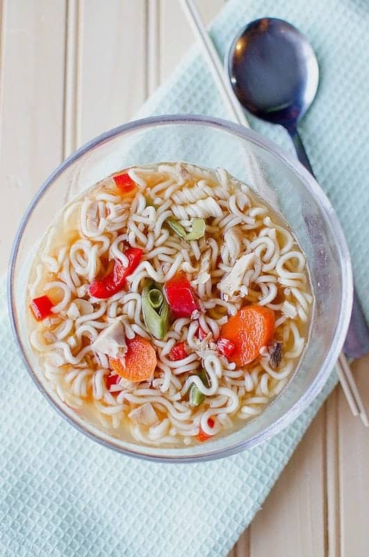 Chicken ramen soup in a glass bowl on a cloth napkin with a spoon