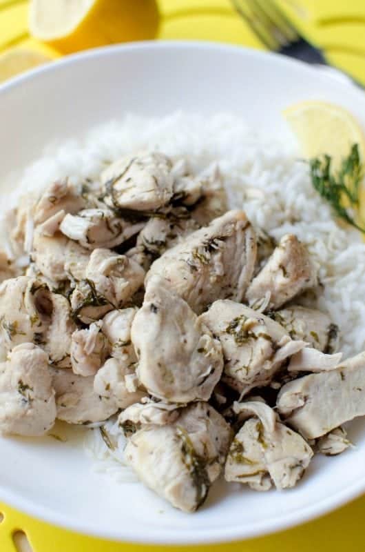  a white plate with chicken, rice, and lemon slices 