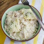 chicken ravioli with cheese garnish in a light green bowl with a fork over it