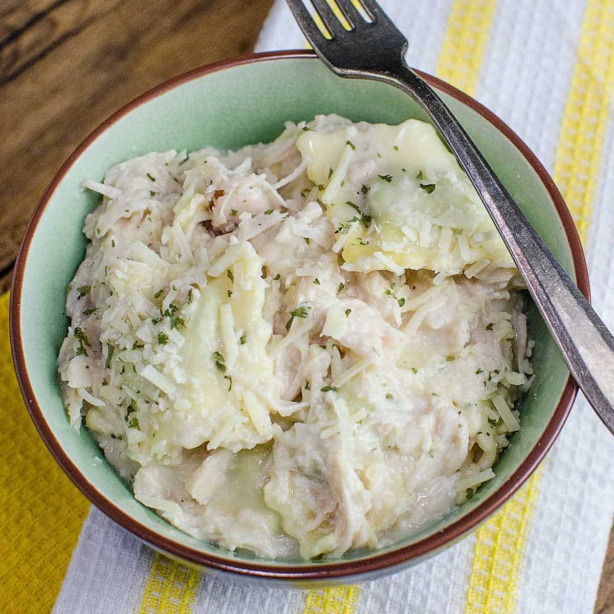 chicken ravioli with cheese garnish in a light green bowl with a fork over it