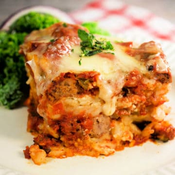 crockpot lasagna on a white plate next to a red checkered napkin