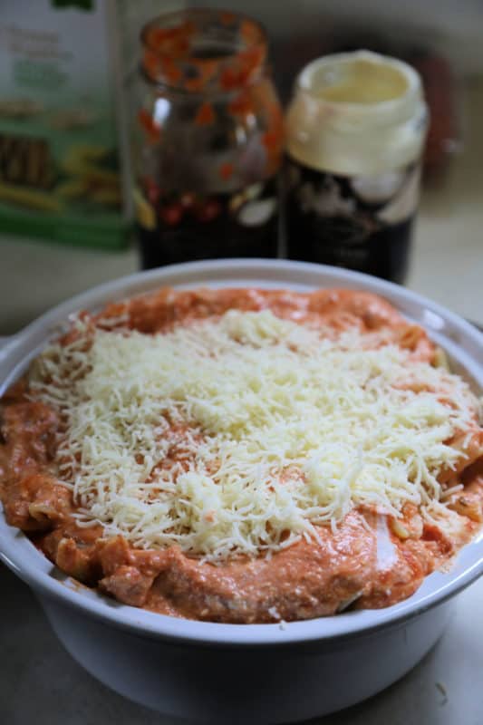 unbaked ziti in a white dish next to empty jars of sauce