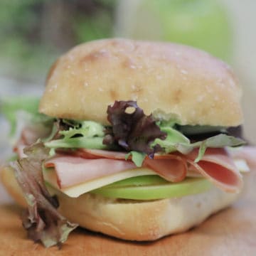 Ham and Swiss Ciabatta Sandwich with Garlic Aioli on a wood board